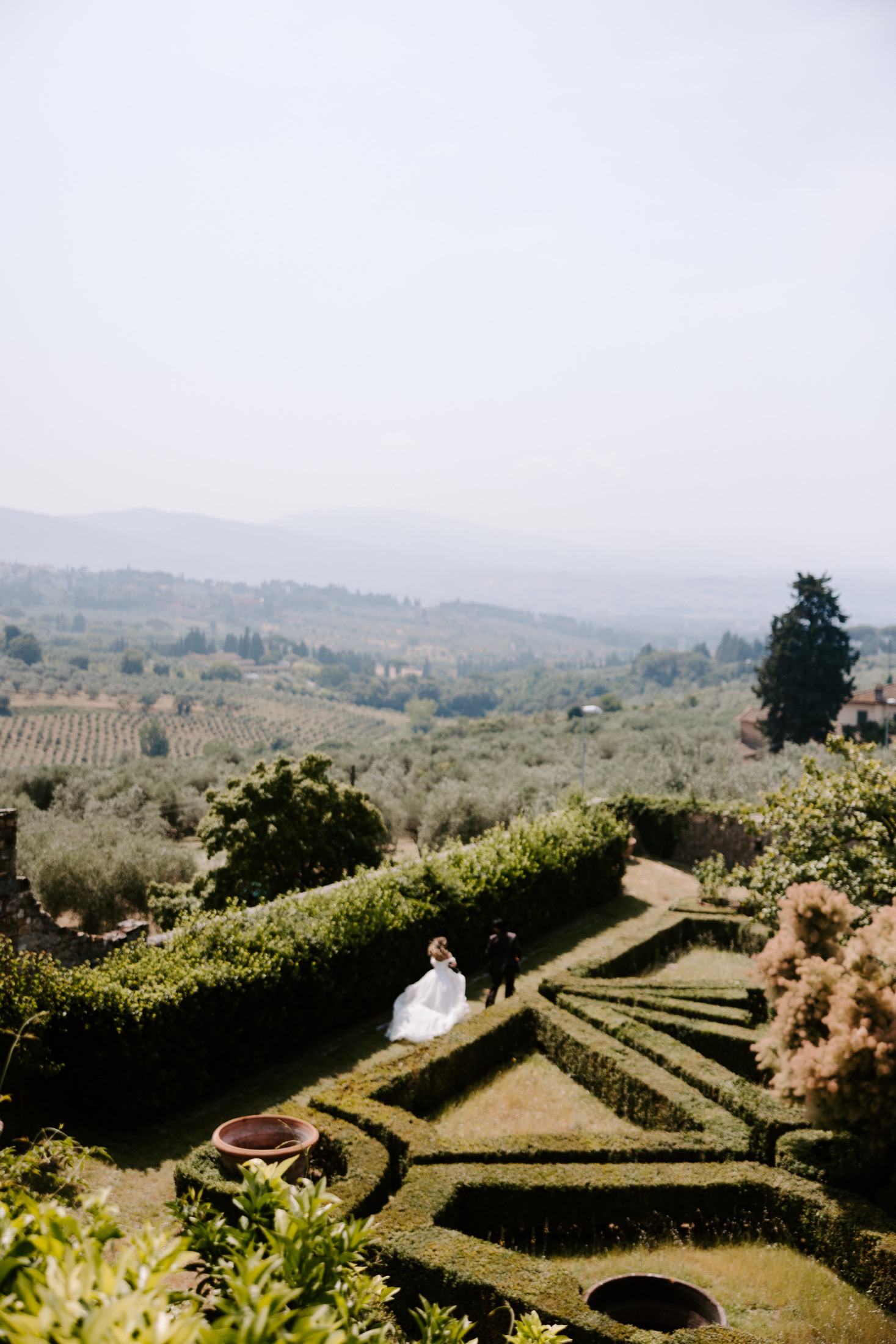 Bride and groom walking through an Italian garden overlooking the countryside