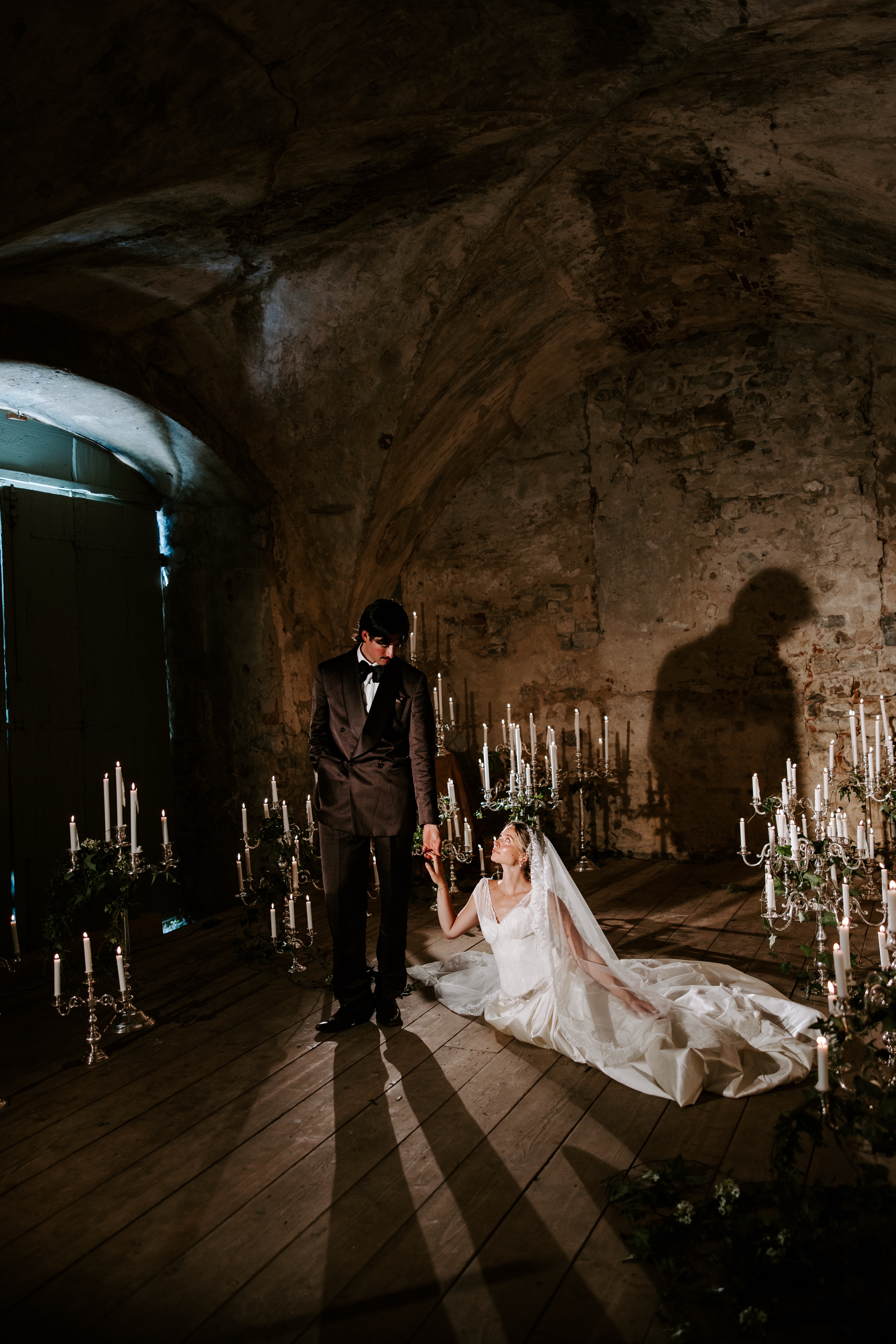 Bride and groom holding hands among candlelit candelabras in an Italian villa
