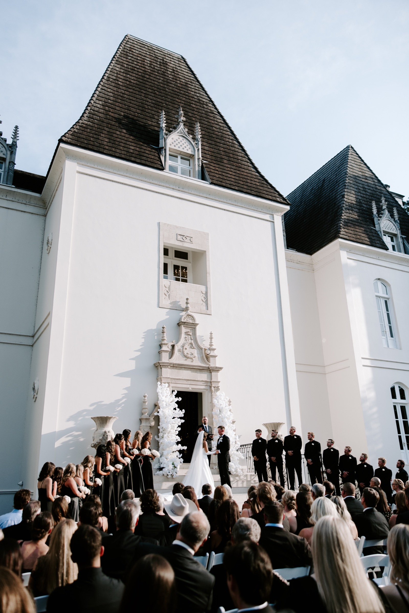 Outdoor wedding ceremony in front of a white chateau