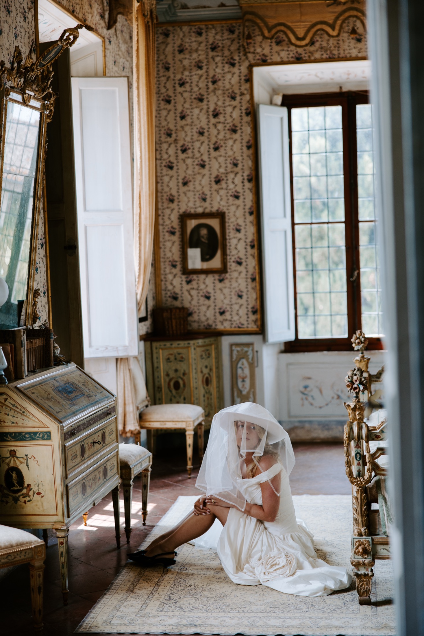 Bride seated beneath her veil in an ornate Italian villa