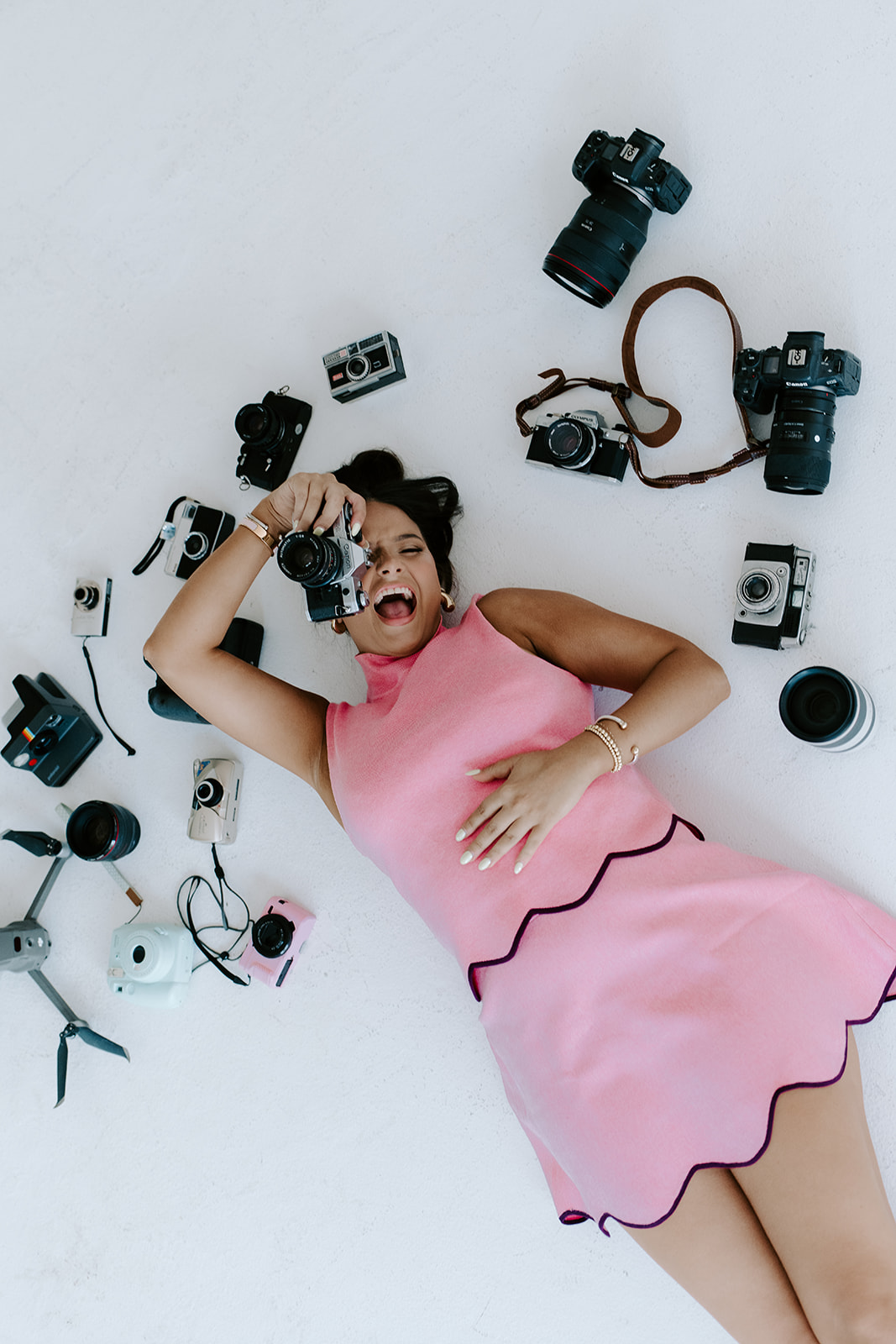 Lily Cox in a pink dress surrounded by her cameras