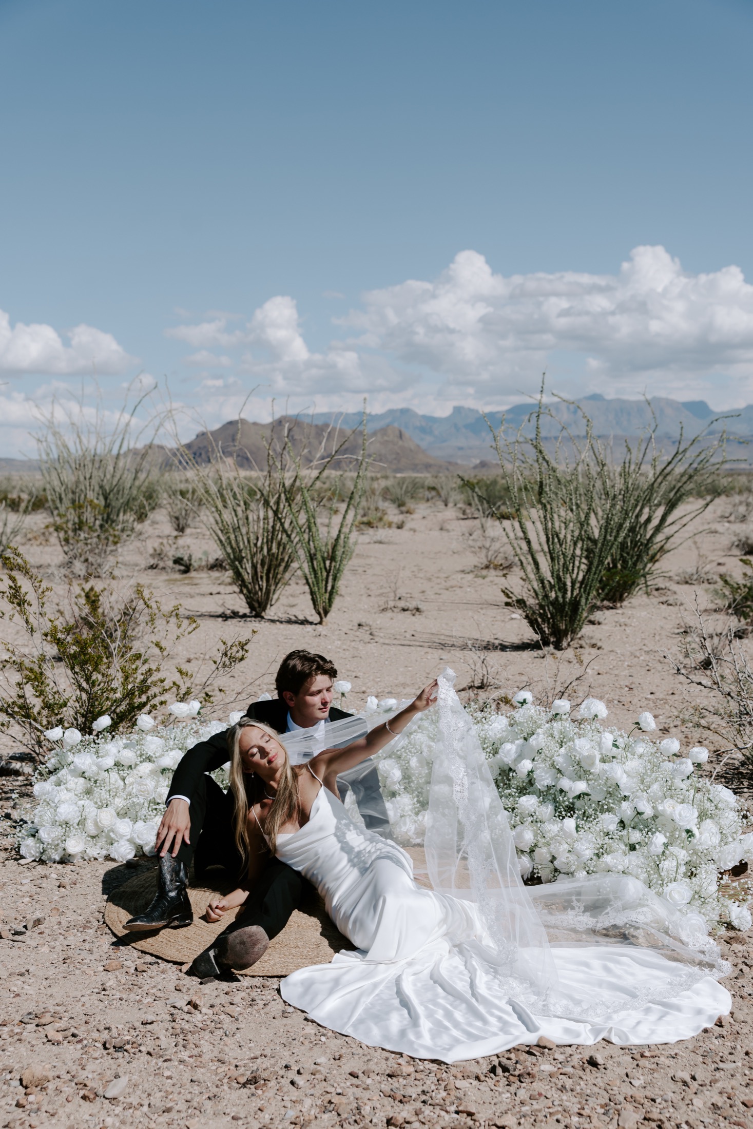 Abby and Luke surrounded by white flowers in the desert