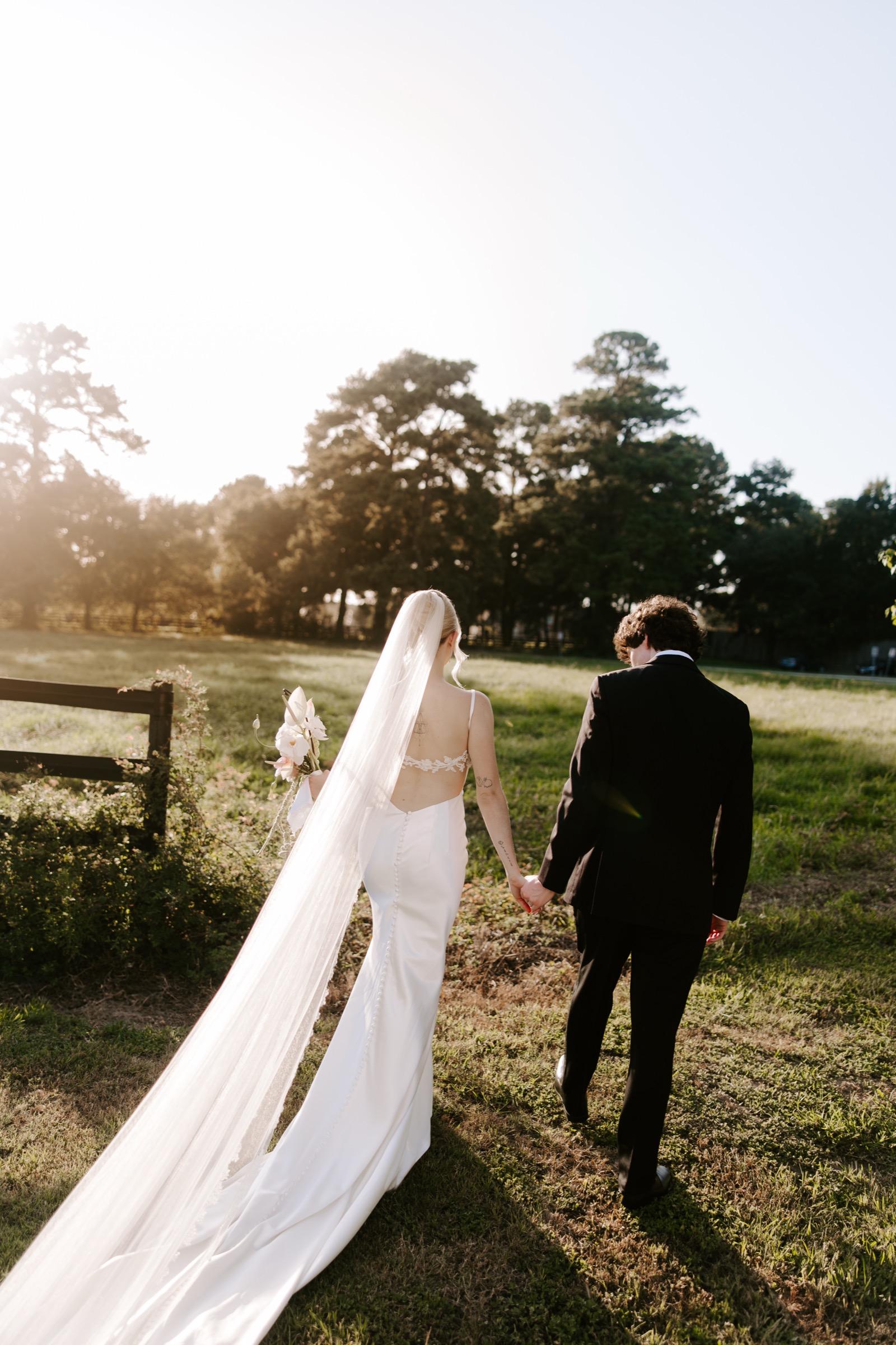 Claire and Nick holding hands in a sunlit field on their wedding day