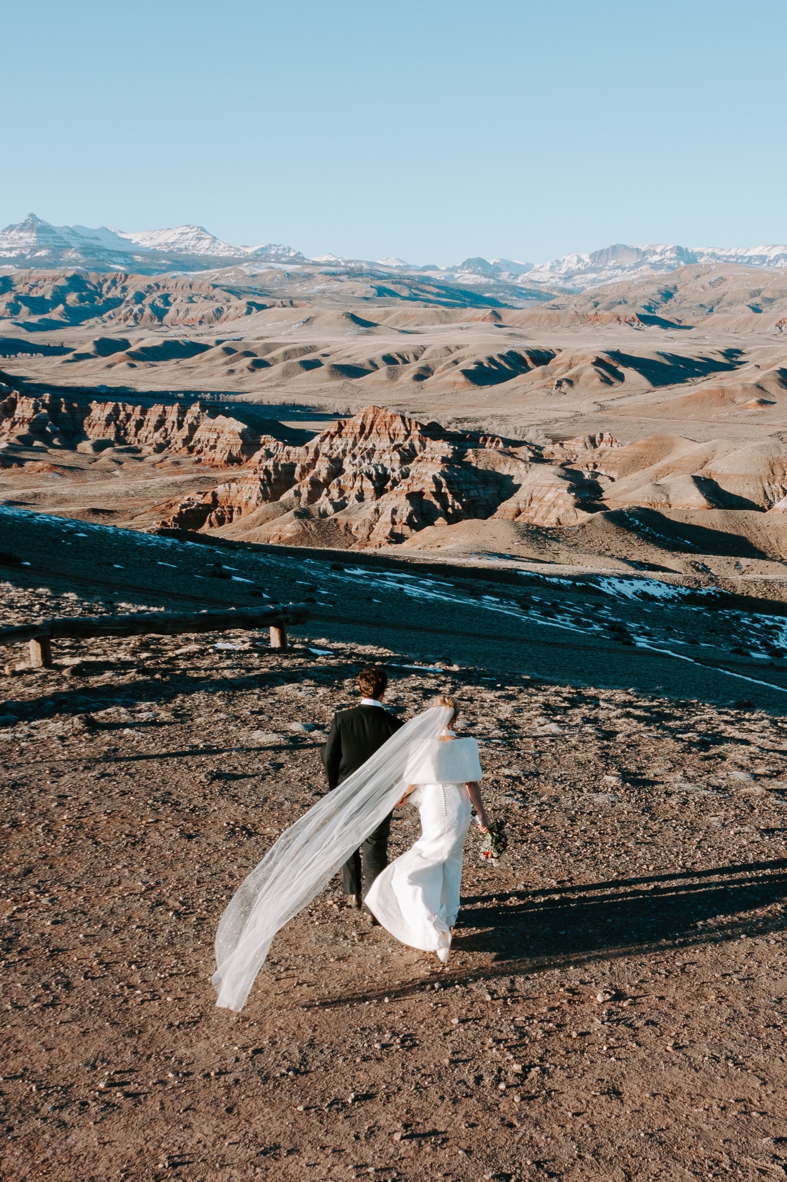 Bride and groom overlooking a dramatic mountain and canyon landscape