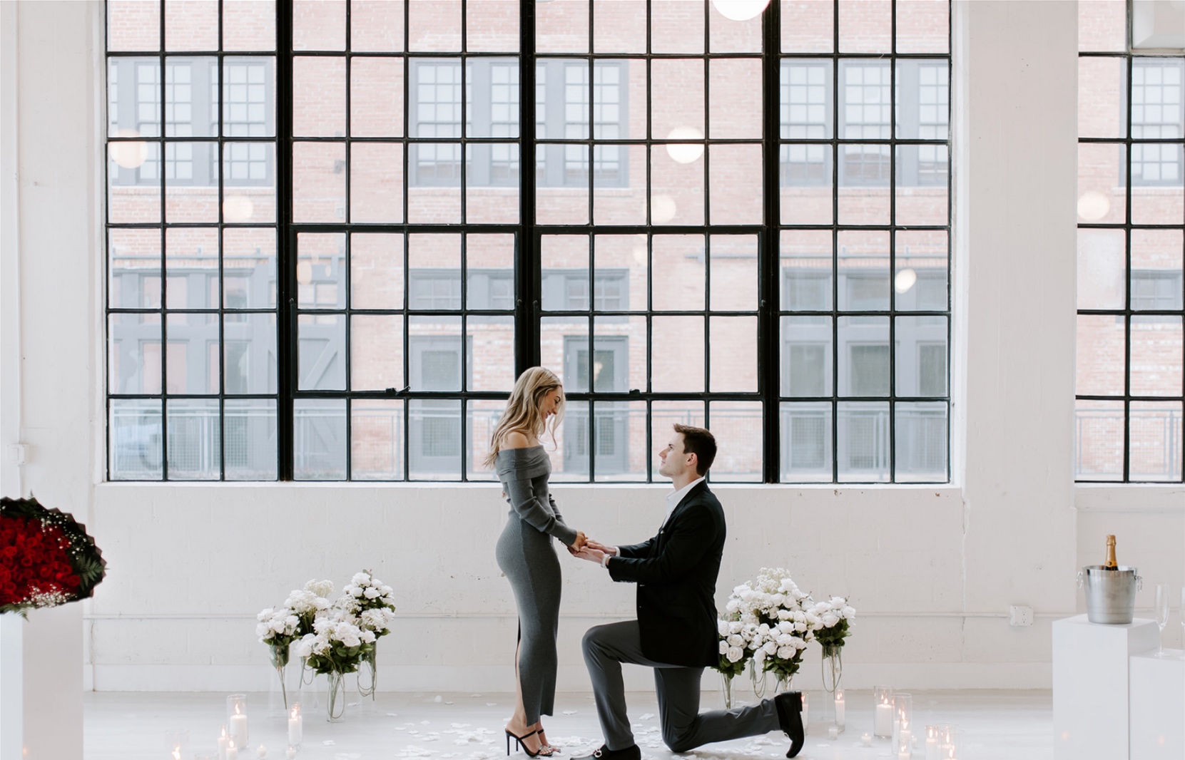 A surprise proposal surrounded by flowers in a window-lit room