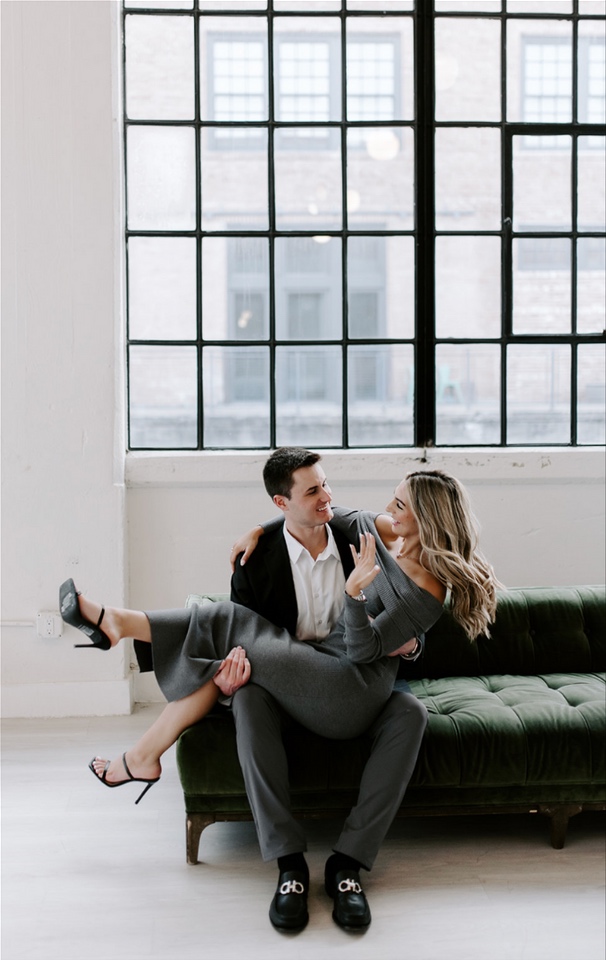 Newly engaged couple laughing together on a sofa