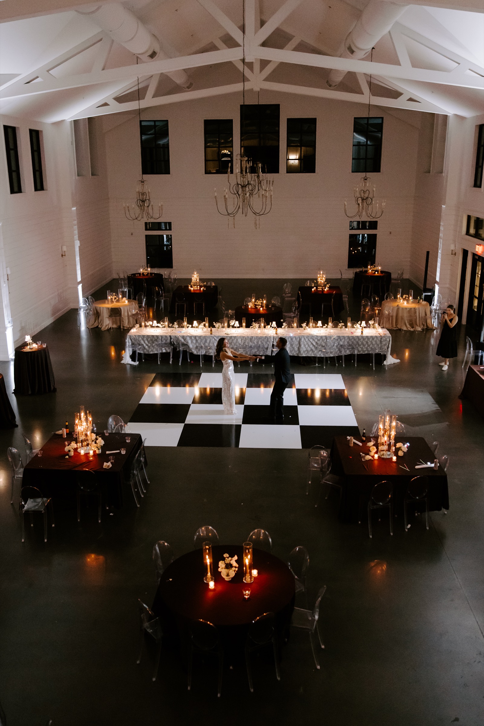 Newlyweds dancing on a checkered floor in a candlelit wedding reception